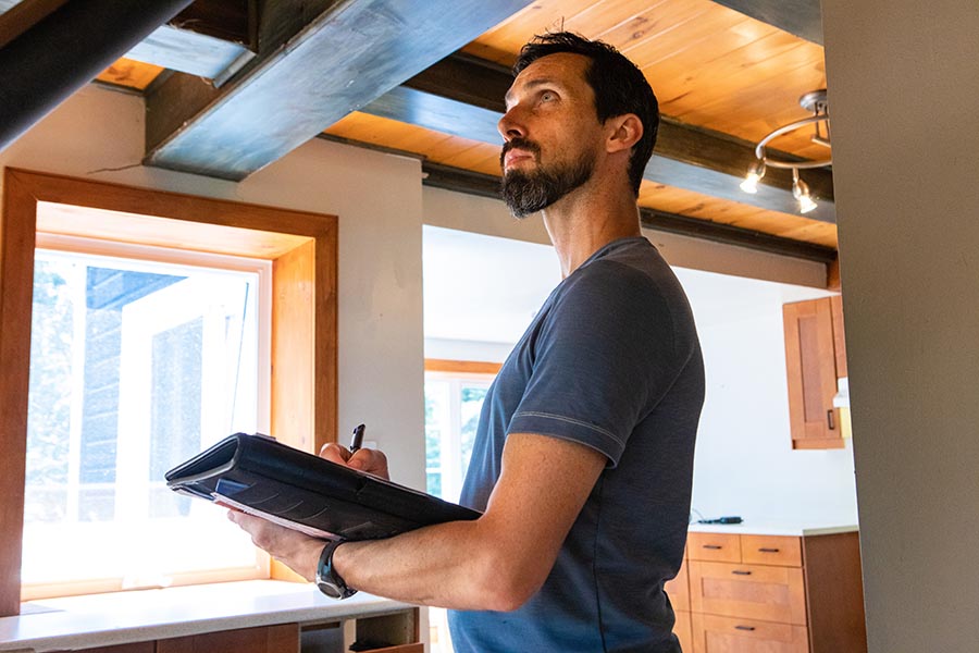 Specialized Business Insurance - Contractor Surveys a Home While Taking Notes With a Clipboard